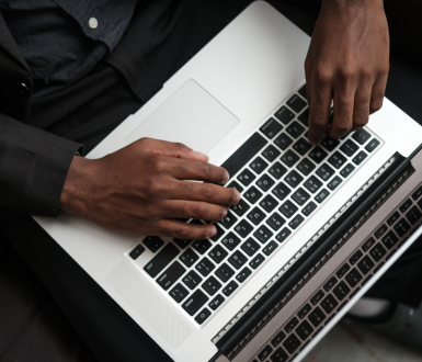 Man Typing MBA Essay on Laptop Keyboard